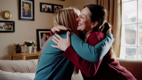 two happy women hugging on a couch in a living room