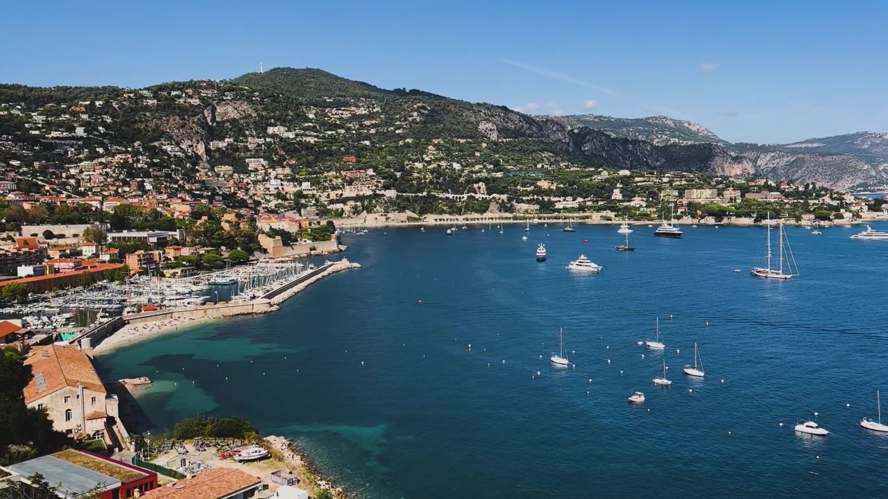 Vista panoramica della baia turchese di Villefranche-sur-Mer, del porto turistico, degli yacht ancorati, delle spiagge e delle case in collina lungo la soleggiata Costa Azzurra