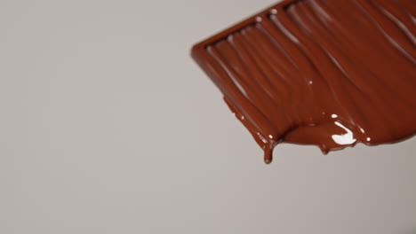 close up of melting chocolate bar against white background with copy space