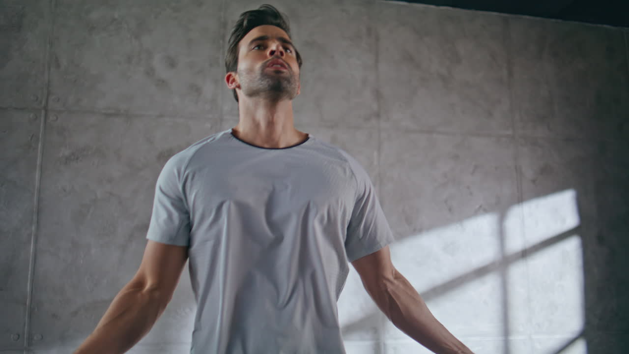 Closeup fitness man jumping in loft sport club. Athlete using skipping rope