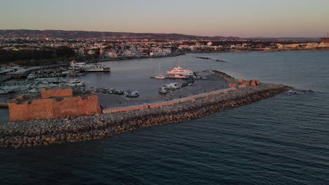 aerial pan of paphos castle set against the sunset with harbor as backdrop, cyprus