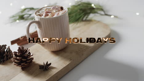 happy holidays text in gold over christmas hot chocolate with marshmallows on white background