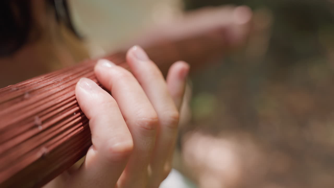 Close up of lady hand gently rotating wooden staff in soft blur forest sunlight, focus on natural texture and graceful motion, symbolizing calm energy, mindfulness, and quiet connection with nature