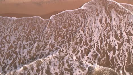 slow motion aerial view of waves breaking in the sandy shore in a caribbean sea beach