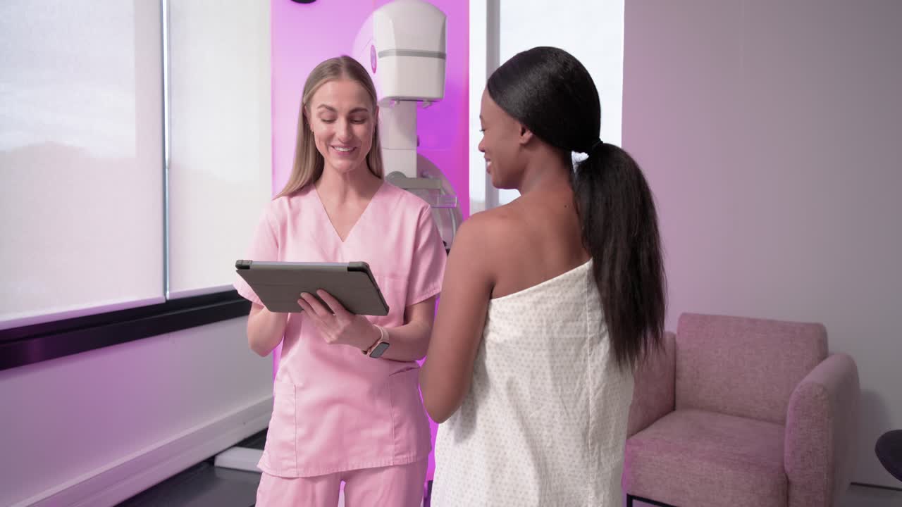 Una clinica donna tiene un tablet, guidando un paziente afroamericano allo scanner e rivedendo le scansioni.