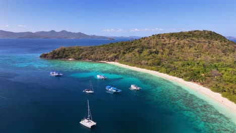 top view of ditaytayan island, with stunning, calm turquoise waters, and some boats at the bay in philippines