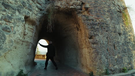 elderly man tourist observes the tunnel inside an ancient defensive castle