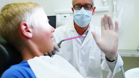 el dentista le da cinco a un joven paciente.