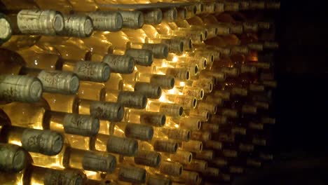 tilt from bottom to top of hundreds of dusty bottles of wine in a wine cellar