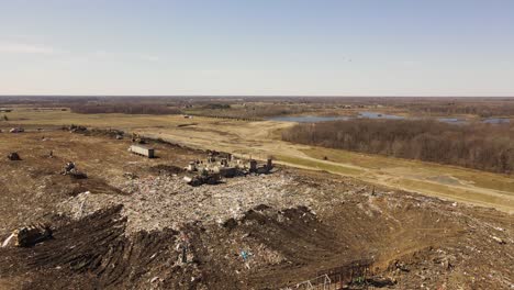 Industrial-vehicles-working-in-landfill-in-Michigan,-aerial-ascend-view