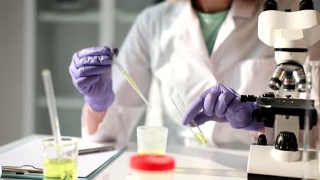 scientist performing laboratory analysis with test tubes and microscope