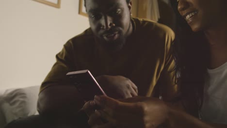 young couple relaxing at home at night in bedroom looking at mobile phone together 3