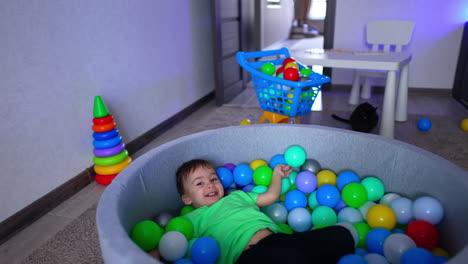 joyful energetic caucasian toddler tumbling in the dry pool. little kid getting out of the basin.
