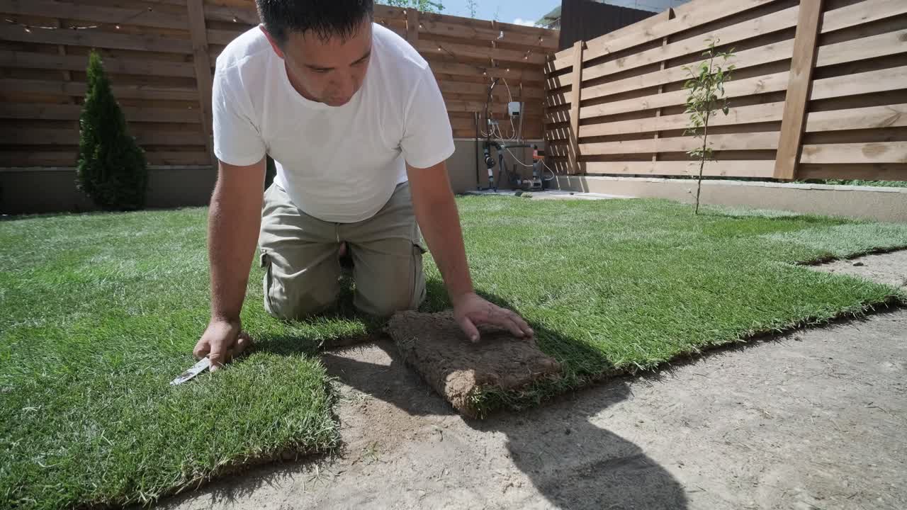 hombre colocando césped en el jardín del patio trasero para la instalación de césped y proyecto de jardinería, centrado en la mejora del hogar y el mantenimiento al aire libre para un césped fresco y verde en un patio residencial