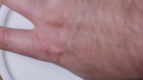 close up of man opening plastic paint can to reveal green paint