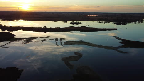 cinematic sunset reflecting on water of swamp, aerial drone view