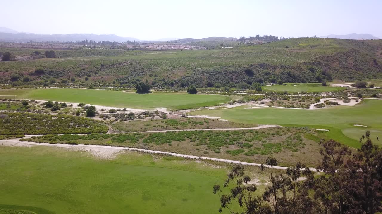 imágenes de drones de 4k de un campo de golf de estilo dune con vistas a las montañas en california en un cálido día de verano al atardecer con jugadores jugando en el fairway y los greens