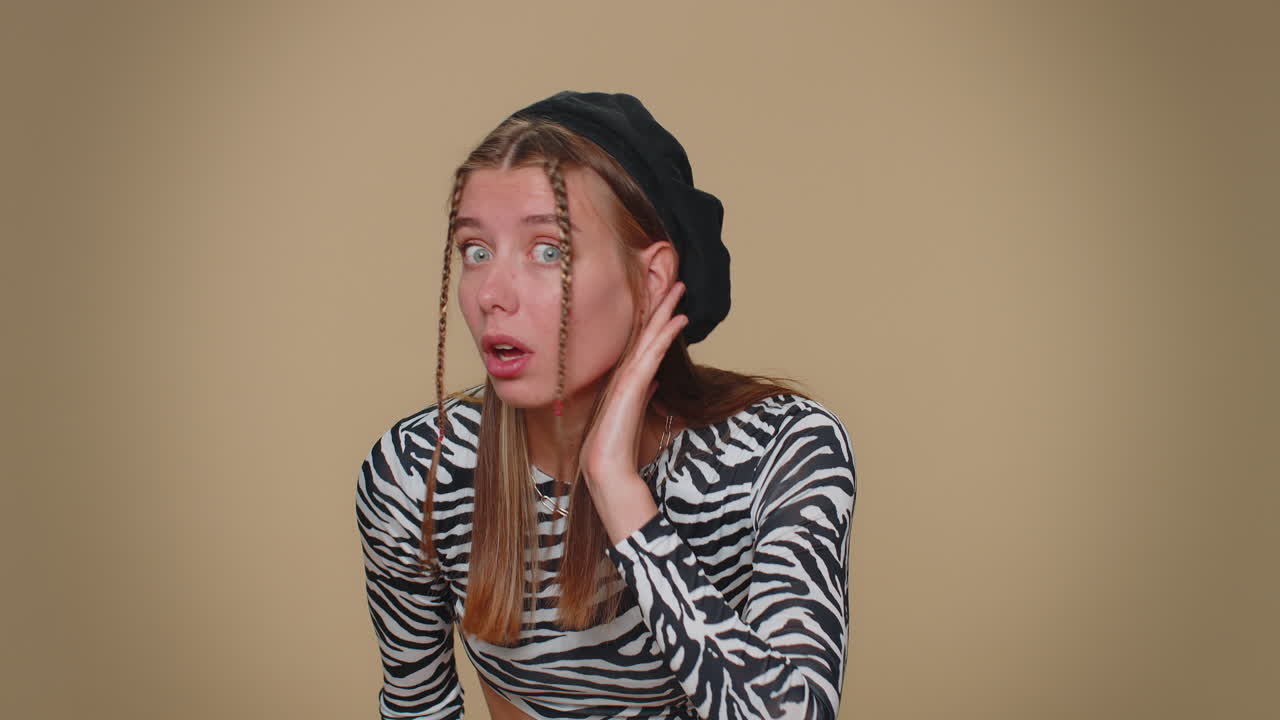 당신을 들으려고 하는 젊은 여성, 혼란스럽고 눈살을  ⁇ 푸리며, 더 큰 목소리를 위해 귀에 팔을  ⁇ 고