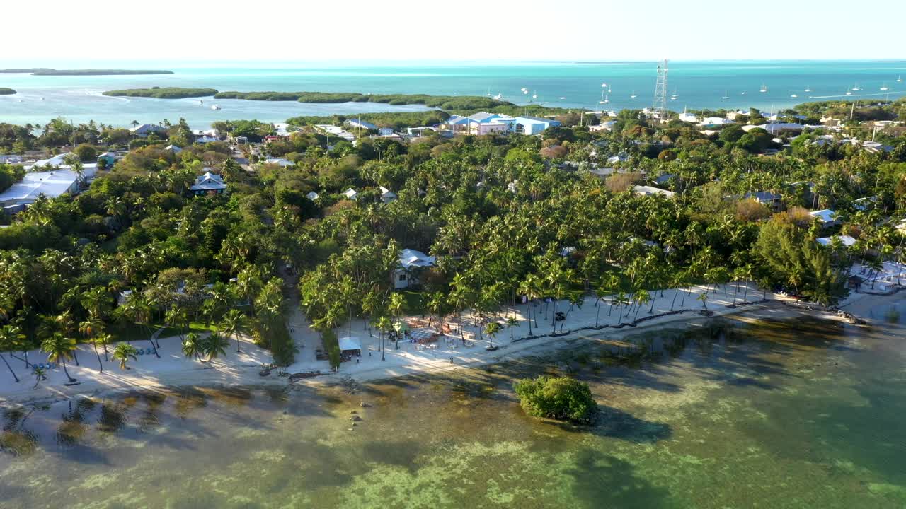 Overhead flyover of forested Florida Keys resort nestled near ocean inlet, establishing aerial