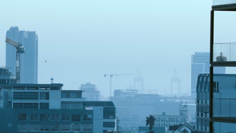 General-view-of-cityscape-with-multiple-modern-buildings-and-construction-site-with-cloudless-sky