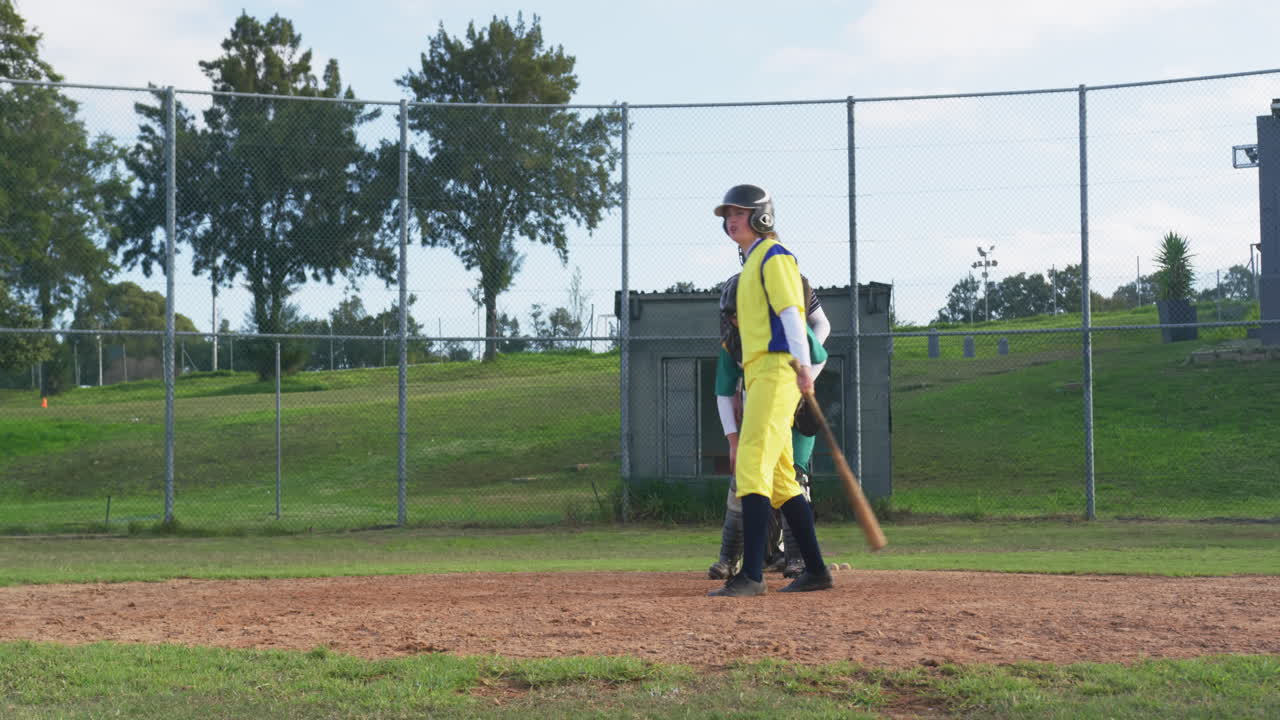 Multiracial female baseball players and male umpire, catching the ball and celebrating on a pitch