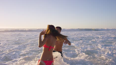 Diverse-Group-of-friends-swimming-in-the-sea-at-sunset