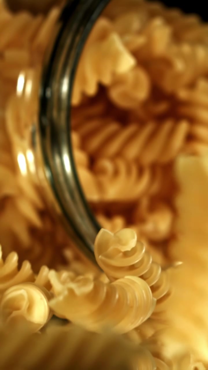 Rallentatore di fusilli crudi che cadono in un barattolo di vetro
