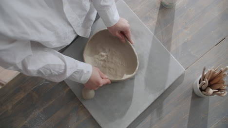 person shaping a clay bowl