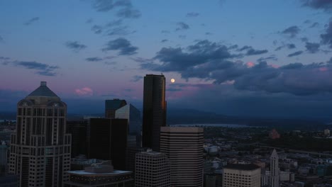 Antena-épica-Del-Crepúsculo-De-La-Luna-Que-Se-Revela-Detrás-De-La-Torre-Columbia-En-El-Horizonte-Del-Centro-De-Seattle