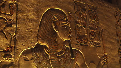 carved wall relief showing an egyptian figure with a long beard and tall headdress, surrounded by hieroglyphs. ancient egyptian art and symbolism preserved in stone