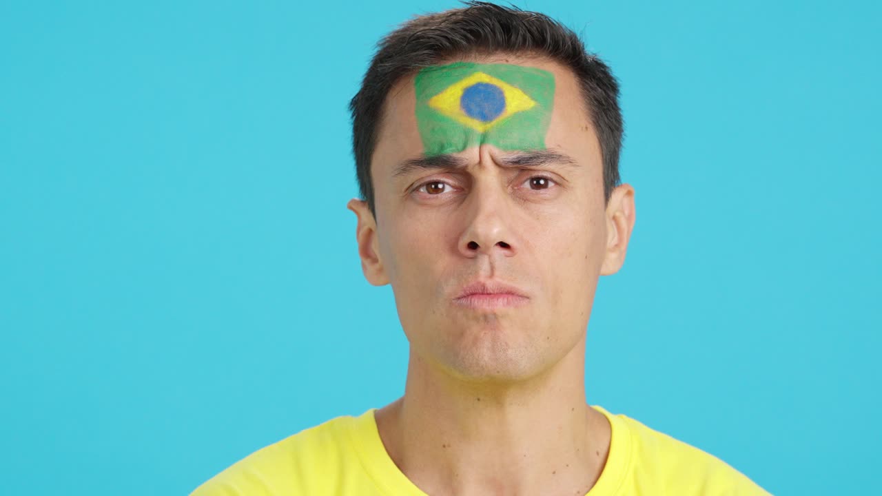 Serious man with a brazilian flag painted on the face