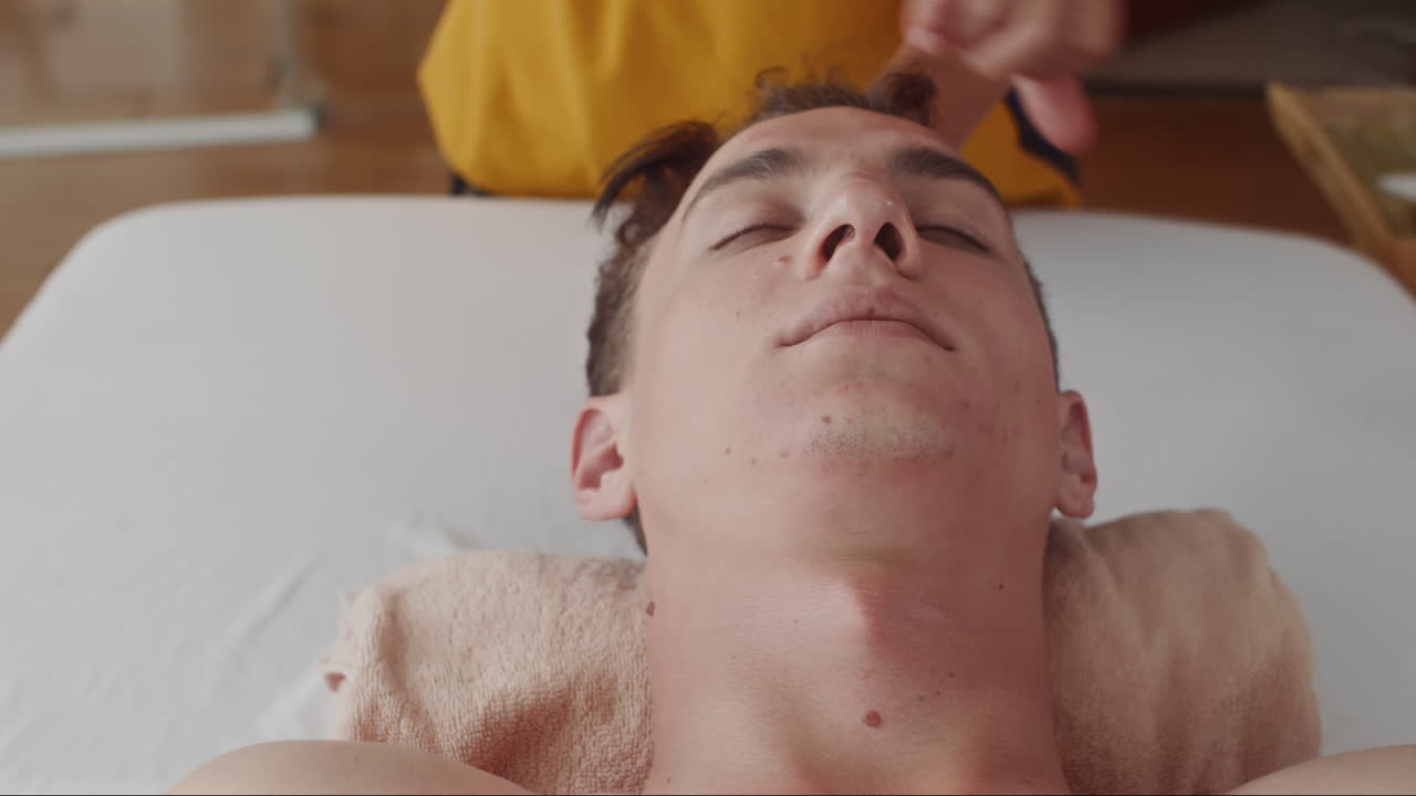 Young Man Enjoying Face Lifting Massage