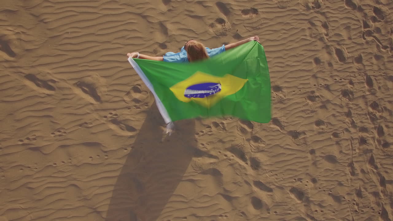 mujer con bandera brasileña ondeando en el viento vista aérea