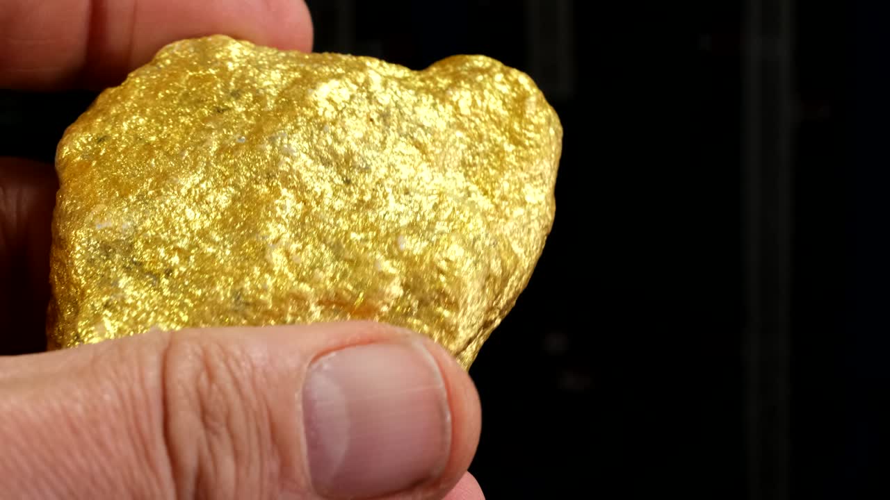 손에 한 조각의 원시 금 조각이 있습니다.