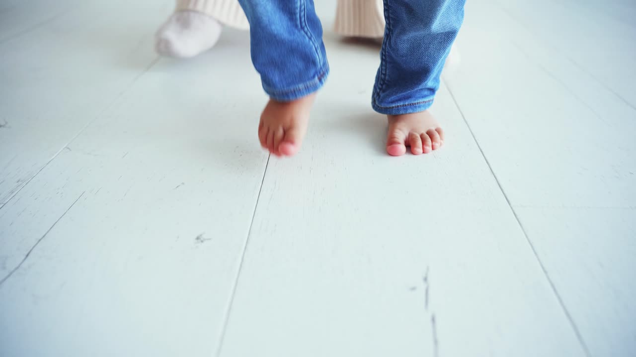 Close-up of Baby's Bare Feet Taking First Steps on White Floor