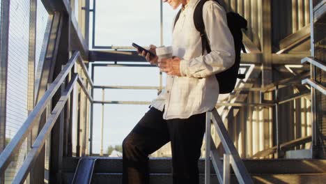 young man walking upstairs with coffee and phone