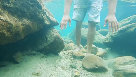 young man holding breath in clear blue water at day from front angle