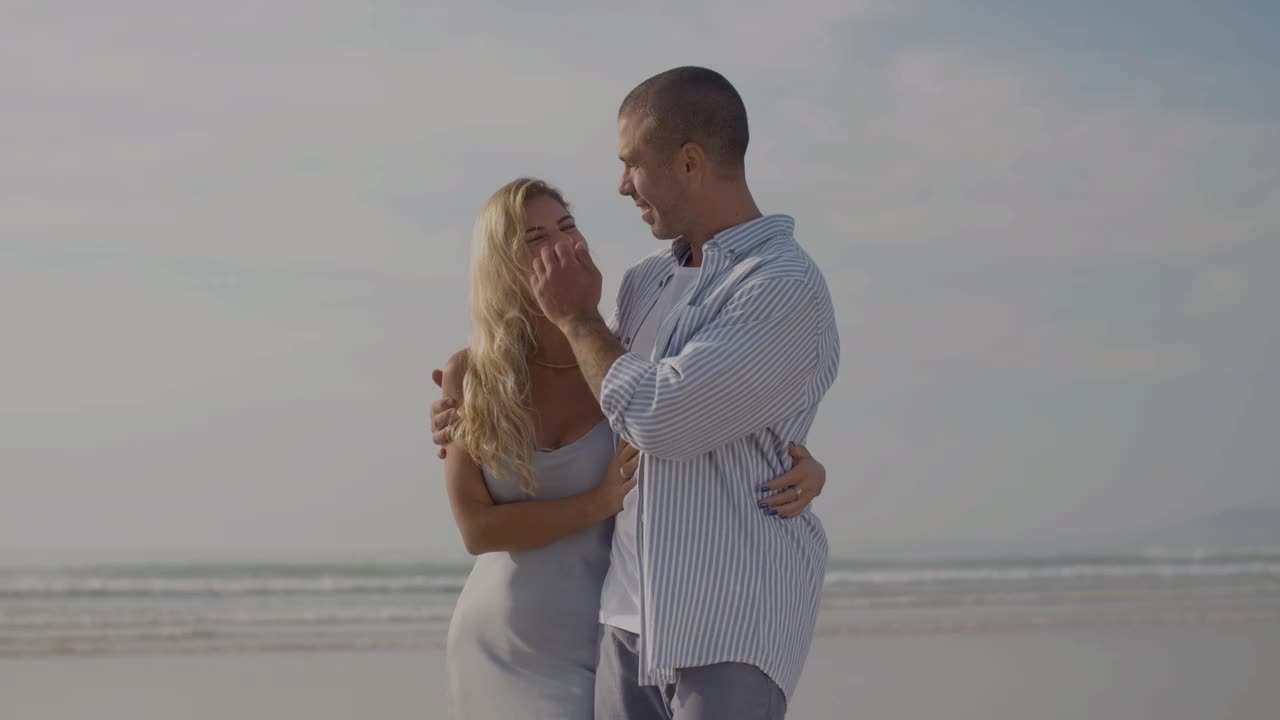 Gelukkig stel dat knuffelend en glimlachend langs het strand wandelt.