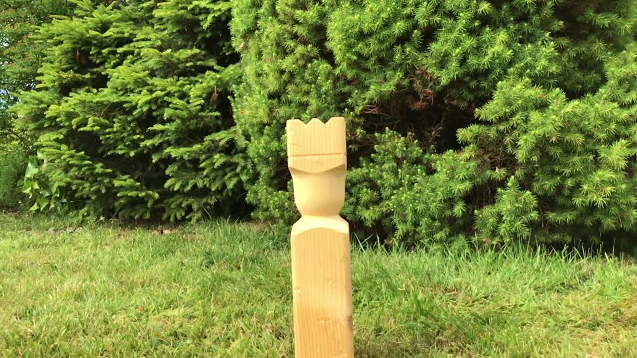 Swedish game kubb. The king gets hit in slow motion. In back garden.