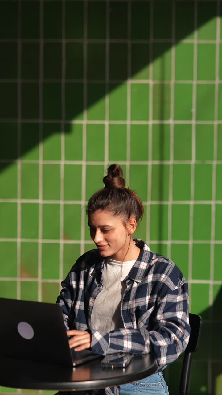 mujer trabajando en una computadora portátil en un café al aire libre