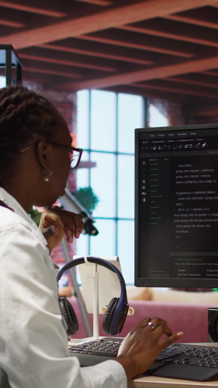 Vertical video Developer at computer desk coding while listening music
