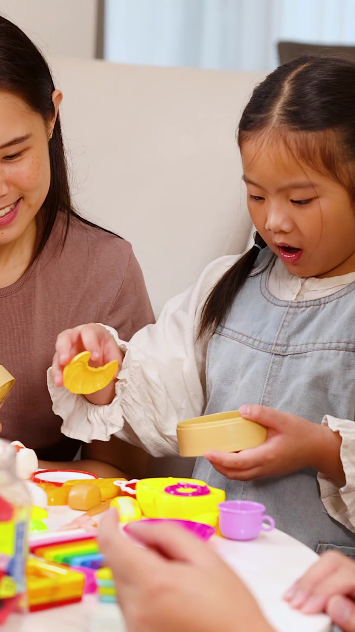 明るい部屋でカラフルなおもちゃの食べ物で遊び、学び、笑う母と娘