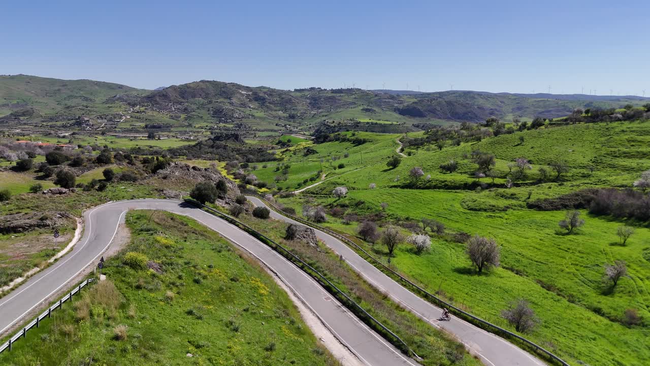 유럽 의 휘어지는 산길 을 자전거 로 내려가는 자전거 타는 사람 의 공중 촬영