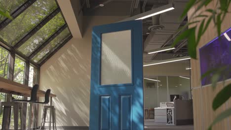 cinematic shot of a blue door in an interior design room with plants and glass windows around