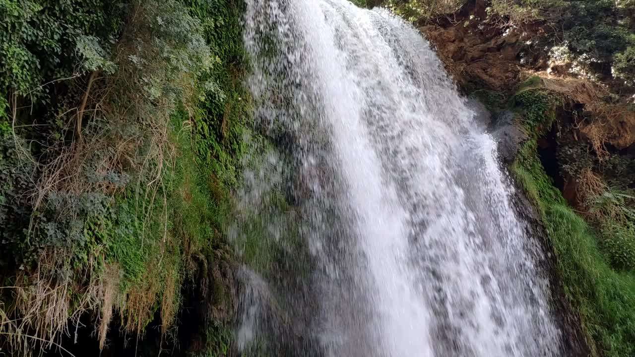 Waterfall cascading over rocks at Monasterio de Piedra, surrounded by lush green foliage