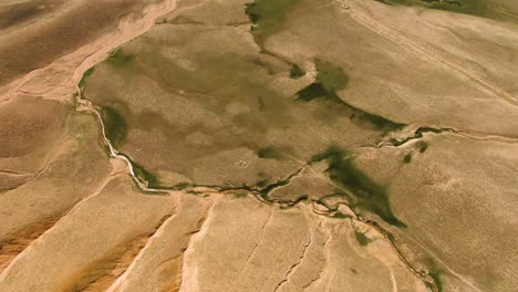 scenic aerial view of arid landscape with stream in namangan region, uzbekistan