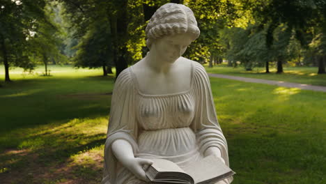 Marble statue of a woman reading a book in a park