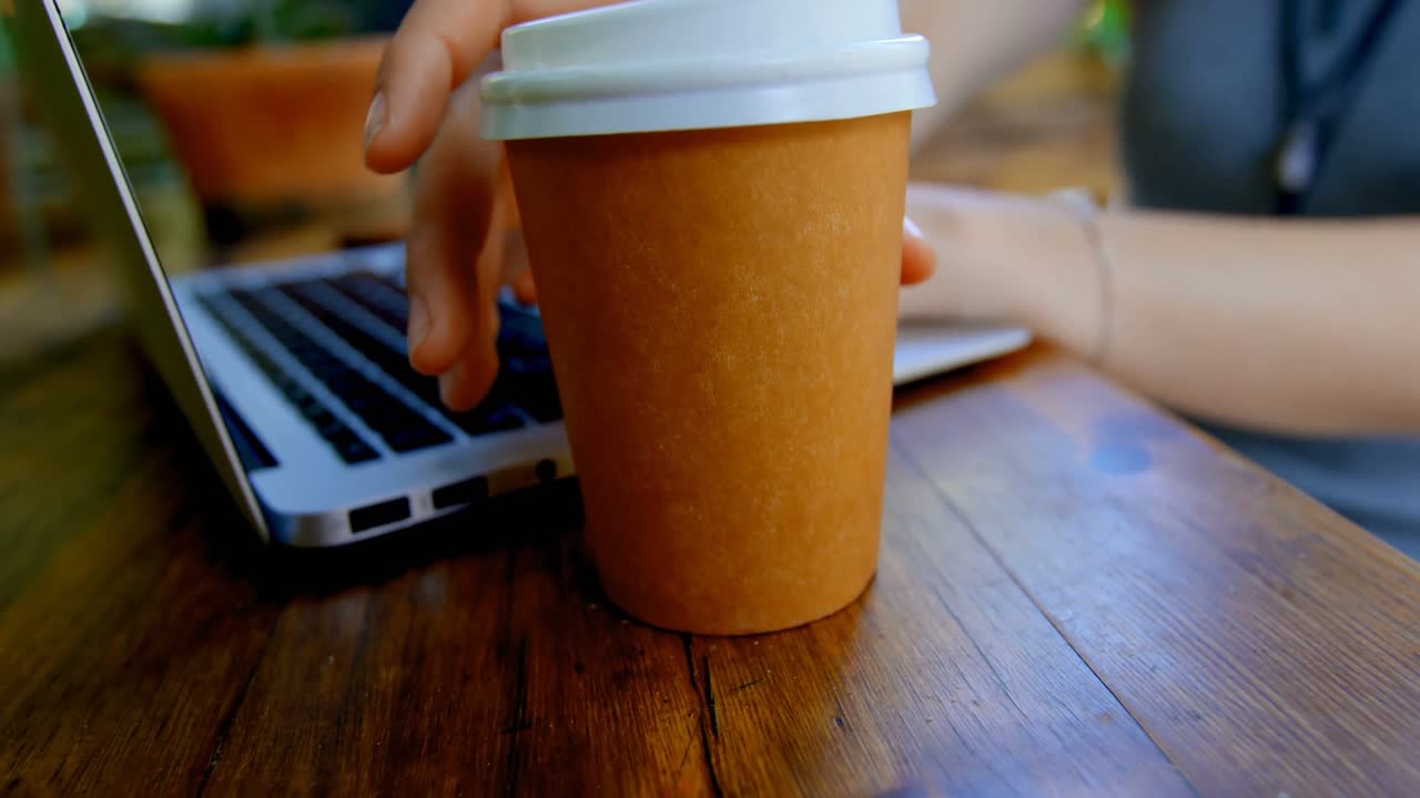 mujer tomando café mientras usa una computadora portátil en un café al aire libre 4k