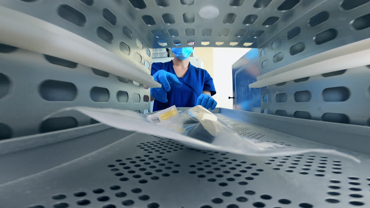 Instrument in plastic bag lies in the sterilizer. Female medic opens the doors and takes away the sterilized tool from the machine.