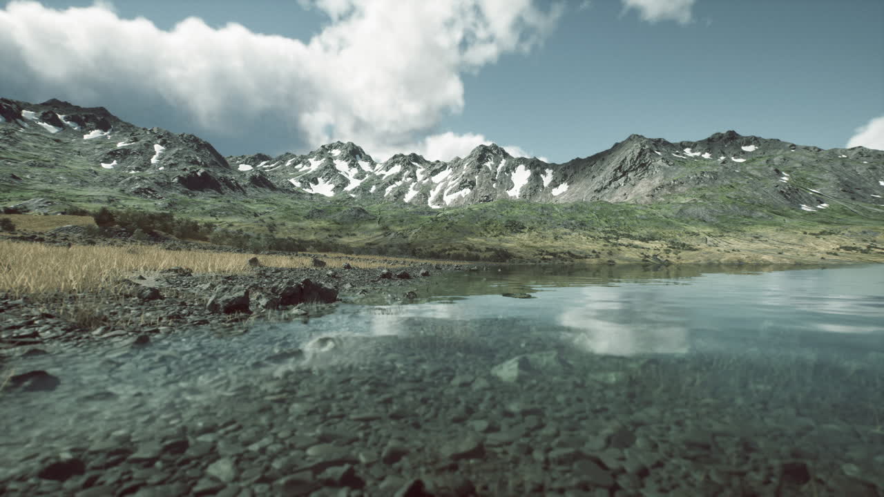 Serene lake reflecting mountains under a partly cloudy sky in summer